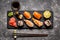 Sushi and sushi rolls, sushi nigiri on stone plate on dark background, mustard wasabi