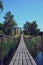 Suspension bridge across the river to the island with a gazebo. Wooden battens are attached between the chains. Handrails from a