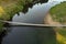 Suspension bridge over a small river, aerial view. Hanging bridge across river. Summer landscape