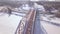 Suspension train bridge through winter river and car traffic on snowy highway aerial view. Railway bridge for train