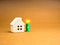 Sustainability at Home concept. Small white toy house near 3d green energy battery power storage symbol.