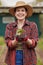 Sustainable farmer holding a plant or seedling outdoors smiling and happy about her organic farm or garden. Young female