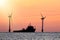 Sustainable resources. Wind farm with ship silhouette at tropical sunrise or sunset. Solar and wind energy and food supply