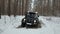 SUV 6x6 overcomes a large puddle on a dirt road in the winter forest