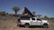 SUV car with camping equipment, rooftop tent, spare tire. Quiver tree forest.