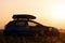 SUV car with roof rack luggage container for off road travelling parked at roadside at sunset