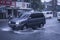 A SUV drives through flooded streets caused by a sudden downpour of heavy rain.