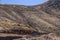 An SUV and a motorcycle take a switchback on a winding mountain road above the tree line - you can see where the road continues on