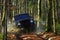 SUV or offroad car on path covered with leaves crossing puddle with water splash. Offroad race on fall nature background