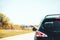 SUV on rural road from back with elegant womans hand out window and blurry background