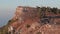 An SUV stands on the edge of a cliff on a mountain. The car stands on a rock against the background of the sea