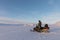 Svalbard, Norway - March 2019: Man standing next to a Yamaha snowmobile in arctic landscape at Svalbard