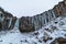 Svartifoss iceland black waterfall completely frozen with bluish stalactites and snow under white sky