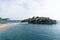 Sveti Stefan island in Budva in a beautiful summer day, Montenegro. Luxury sand beach with wooden chaise-longue chairs and