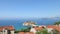 Sveti Stefan island panning by horizon. Seacoast with old stone buildings. Sunny day blue sky clouds. Top view resort