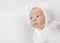 Swaddled funny newborn in white hat with curious eyes