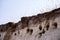 Swallow`s nests in the sand in a steep cliff of the river bank on a summer day