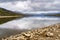 Swamp landscape with reflections in the water of the mountains and shore with large rustic stones