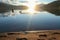 A swan crossing the Millstaetter lake in Austria during the sunset. The lake is surrounded by high Alps. Calm surface