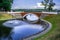 Swan pond with fountain and red footbridge.