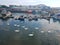 Swans gliding along the water in England in front of fishing boats