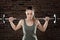 Sweat fit woman lifting dumbbells on brick background