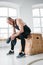 Sweaty muscular man sitting on box in crossfit gym