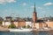 Sweden capital cityscape with tower of Riddarholm Church and touristic ship on water. Stockholm at sunny day