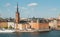 Sweden capital cityscape with tower of Riddarholm Church and touristic ship on water. Stockholm at sunny day