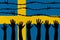 Sweden flag behind barbed wire fence. Group of people hands. Freedom and propaganda concept