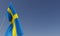 Sweden flag on flagpole on blue background. Place for text. The flag is unfurling in wind. Swedish, Stockholm. Europe. 3D