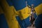 Sweden flag with statue of lady justice and judicial scales in dark room. Concept of judgement and punishment