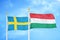 Sweden and Hungary two flags on flagpoles and blue sky