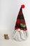 Swedish gnome in gray clothes and a plaid hat with wood on a white background