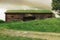 A Swedish house 500 years old with grass on its roof, in the middle of a meadow with a rainbow above