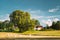 Swedish Rural Landscape Field With Dry Hay Bales Rolls After Harvest In Sunny Evening. Farmland With Red Farm Barn In