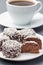 Swedish sweets chocolate balls or chokladbollar, made from oats, cocoa, butter and coconut, on white plate, served with coffee,