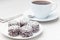 Swedish sweets chocolate balls or chokladbollar, made from oats, cocoa, butter and coconut, on white plate, served with coffee,