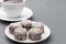 Swedish sweets chocolate balls or chokladbollar, made from oats, cocoa, butter and coconut, on white plate, served with coffee,