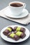 Swedish sweets punsch rolls or punschrullar, covered with green marzipan, on white plate, served with coffee,  vertical