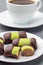 Swedish sweets punsch rolls or punschrullar, covered with green marzipan, on a white plate, served with coffee,  vertical