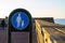 A Swedish walkway sign close to a pier. People walking in the background as the sun sets