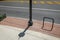 Sweep of asphalt city street with yellow and white lines bordered by a red brick and concrete sidewalk, street light and empty bik