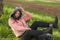 Sweet Asian woman in hoodie making faces - lifestyle portrait of young happy and beautiful Japanese girl sitting playful on green