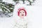 Sweet baby girl in white jacket sitting under snowy christmas tree