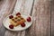 Sweet baked Belgian waffles with chocolate filling on a beige plate, decorated with red cherries, on a brown wooden background