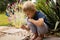 Sweet barefoot toddler child, playing with snail after rain in garden