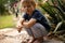 Sweet barefoot toddler child, playing with snail after rain in garden