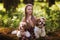 Sweet beautiful girl hugs two identical Shih Tzu dogs on a clearing in the forest