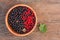 Sweet, black and red currant and green leaves in wooden bowl.